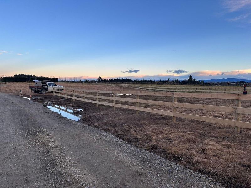 New post and rail fence running away to the horizon at dusk, with the ute parked at the far end