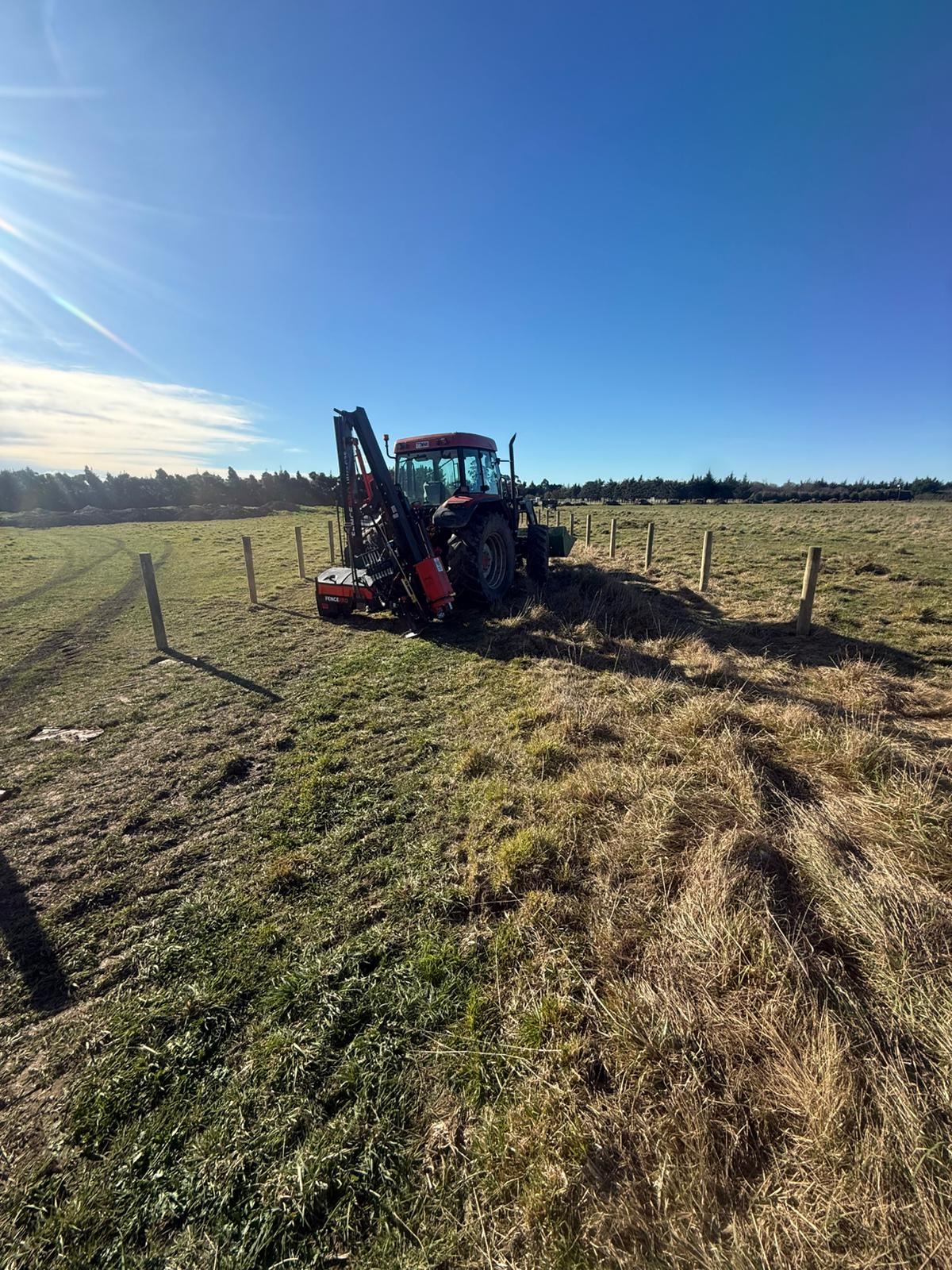 The tractor-mounted post driver at work on a fence line